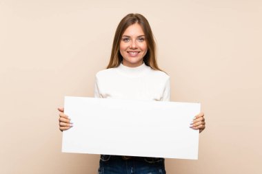 İzole edilmiş arka planda genç sarışın bir kadın bir konsept eklemek için beyaz bir levha tutuyor.
