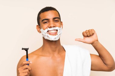 Genç yakışıklı adam sakalını soyutlanmış arka planda tıraş ederken gururlu ve kendini beğenmiş.