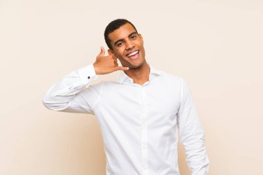 Genç, yakışıklı, esmer bir adam izole edilmiş arka planda telefon jesti yapıyor. Bana geri dönüş işareti ver.