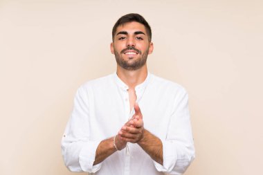 Arkaplanda sakallı yakışıklı bir adam alkışlıyor.