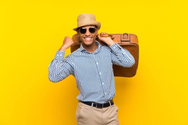 Esmer adam, izole edilmiş sarı arka planda eski bir evrak çantası tutuyor ve zaferi kutluyor.