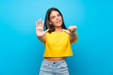İzole edilmiş mavi arka planda altı parmaklı genç kız.