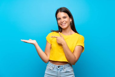 Bir reklam eklemek için avuç üzerinde copyspace hayali tutan izole mavi arka plan üzerinde Genç kız