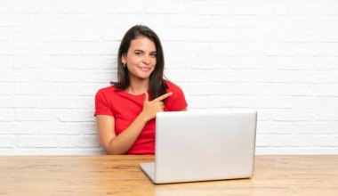 Yan parmak işaret eden bir masada pc ile genç kız