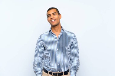 Genç, yakışıklı, esmer adam soyutlanmış mavi arka planda gülüyor.