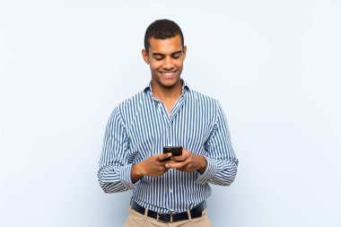 Izole mavi arka plan üzerinde genç yakışıklı esmer adam mobil ile bir mesaj gönderme