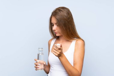 Tecrit edilmiş arka planda bir şişe suyu olan genç sarışın kız.