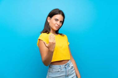 İzole edilmiş mavi arka planı olan genç bir kız, bizimle gelmesi için davet ediyor. Gelmene sevindim.