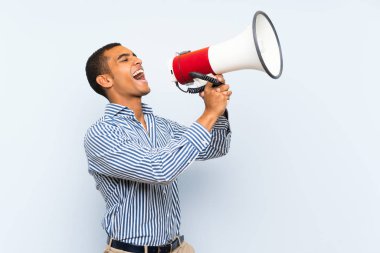 Bir megafon ile bağırarak izole mavi arka plan üzerinde Genç yakışıklı esmer adam