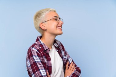 Mavi duvar ayakta ve yan bakarak üzerinde beyaz kısa saçlı genç kız