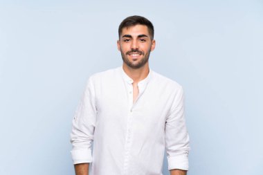 Sakallı yakışıklı, soyutlanmış mavi arka planda gülüyor.