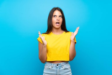 İzole edilmiş mavi arka planı olan genç bir kız kötü bir durum yüzünden hayal kırıklığına uğradı.