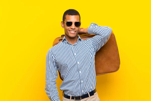 Hombre morena sosteniendo un maletín vintage sobre fondo amarillo aislado —  Fotos de Stock