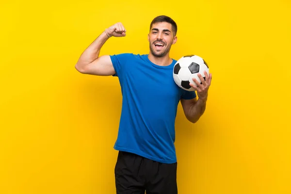 Młody przystojny piłkarz człowiek nad białym ścianie żółty — Zdjęcie stockowe