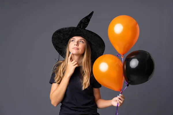 Молодая Ведьма Держит Черные Оранжевые Воздушные Шары Думая Идее — стоковое фото