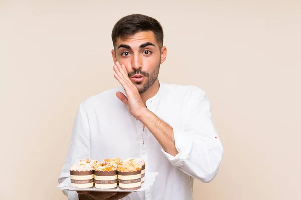 Knappe Man Met Muffin Cake Geïsoleerde Achtergrond Fluisterend Iets — Stockfoto