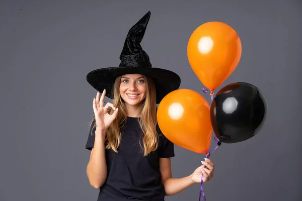 Young Witch Holding Black Orange Air Balloons Showing Sign Fingers — 스톡 사진