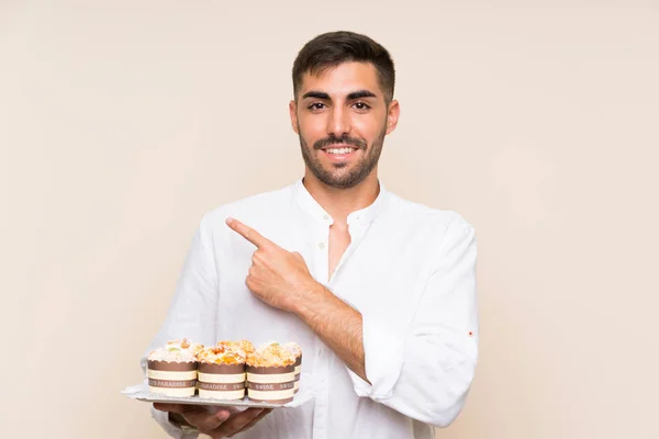 Knappe Man Met Muffin Cake Geïsoleerde Achtergrond Wijzend Naar Zijkant — Stockfoto