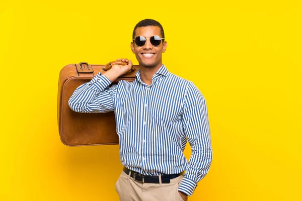 Brunette man holding a vintage briefcase over isolated yellow background — Stock Photo, Image