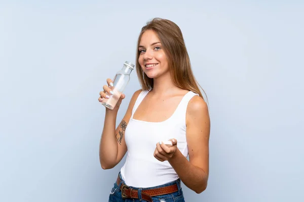 Chica rubia joven con una botella de agua sobre un fondo aislado —  Fotos de Stock