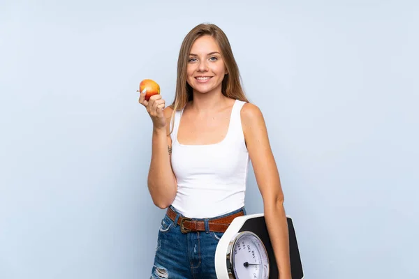 Fiatal szőke lány mérleg gép és egy alma át i — Stock Fotó