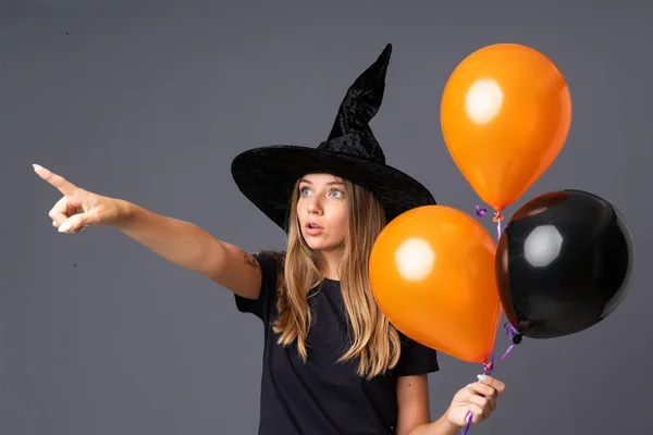 Молодая Ведьма Держит Черные Оранжевые Воздушные Шары Указывающие Сторону — стоковое фото