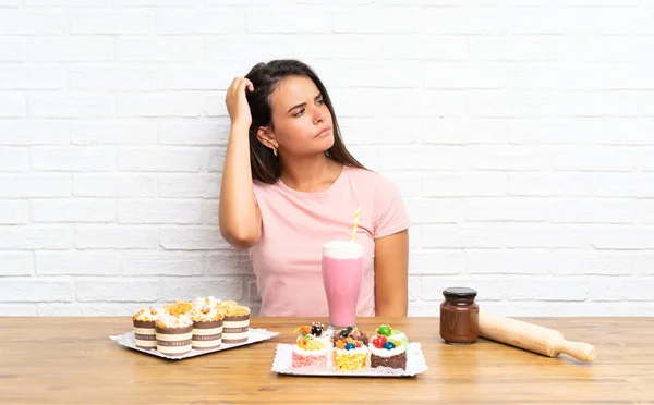 Junges Mädchen Mit Vielen Verschiedenen Mini Kuchen Mit Zweifeln Und — Stockfoto