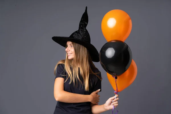 Молодая Ведьма Держит Черные Оранжевые Воздушные Шары Глядя Сторону — стоковое фото