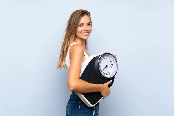 Giovane ragazza bionda con pesatrice oltre isolato blu bianco — Foto Stock