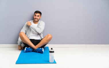 Spor adamı yerde oturmuş zaferi kutluyor.