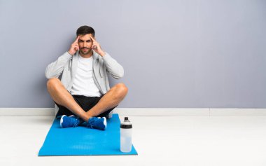 Spor adamı bir yerde mutsuz ve hayal kırıklığına uğramış bir şekilde oturuyor. Olumsuz yüz ifadesi