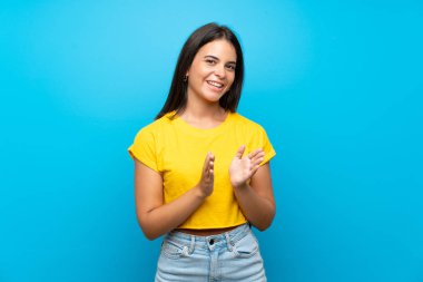 Soyutlanmış mavi arka planda genç bir kız bir konferanstan sonra alkışlıyor.