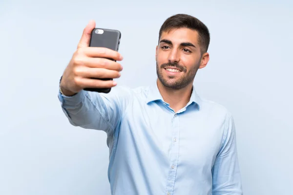 Jovem bonitão com seu celular fazendo uma selfie — Fotografia de Stock
