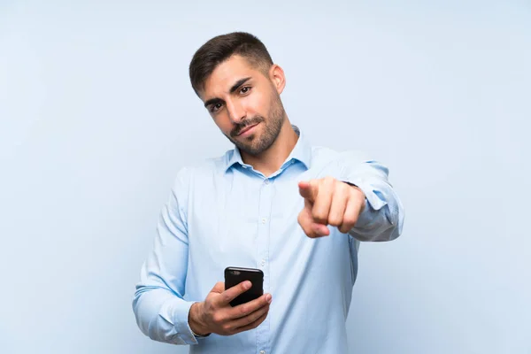 Junger Gutaussehender Mann Mit Handy Über Isolierter Blauer Wand Zeigt — Stockfoto