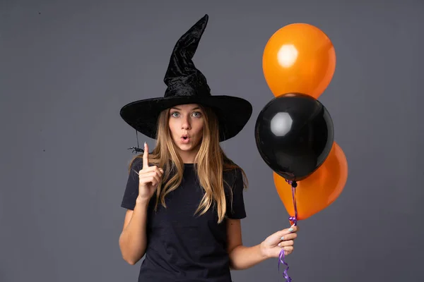 Молодая Ведьма Держит Черные Оранжевые Воздушные Шары Удивительным Выражением Лица — стоковое фото