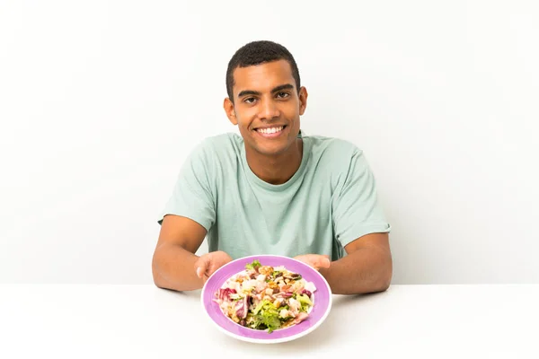 Ung stilig man med sallad i ett bord — Stockfoto