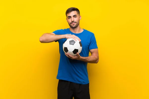 Giovane giocatore di calcio bello uomo oltre isolato muro giallo — Foto Stock