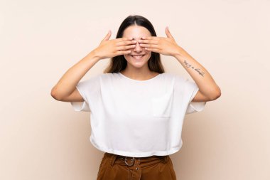 Genç esmer kadın izole edilmiş arka planda gözlerini elleriyle kapatıyor.