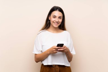 Genç esmer kadın izole edilmiş arka planda cep telefonuyla bir mesaj gönderiyor.