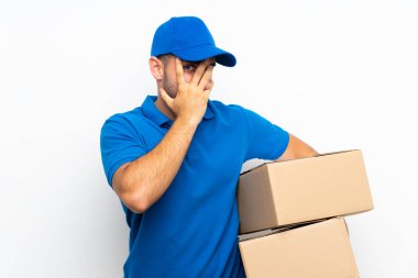 Teslimatçı, izole edilmiş beyaz arka planda gözleri kapatıyor ve parmaklarından bakıyor.