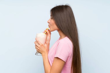 Izole mavi arka plan üzerinde çilek milkshake ile genç kadın