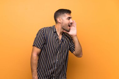 Arkaplanda sakallı yakışıklı bir adam ağzı sonuna kadar açık bağırıyor.