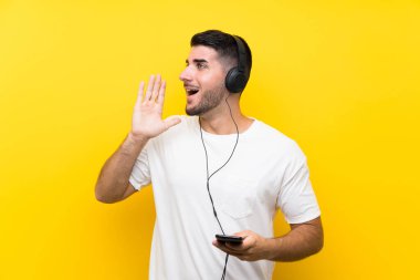 Genç yakışıklı adam müzik dinliyor. Seyyar, izole edilmiş sarı duvarı var. Ağzı açık bağırıyor.