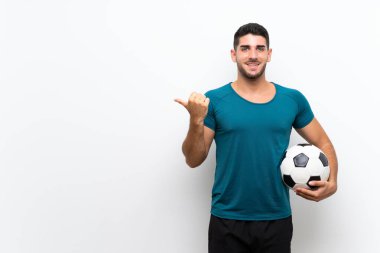 Yakışıklı genç futbolcu izole beyaz duvar üzerinde bir ürün sunmak için yan işaret