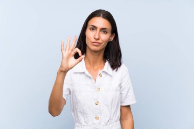 Parmakları ile ok işareti gösteren izole mavi arka plan üzerinde genç kadın