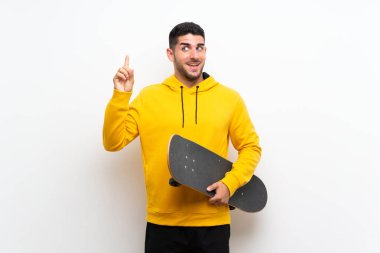 Yakışıklı genç kaykaycı, izole edilmiş beyaz duvarın üzerinden parmağını kaldırarak çözümü anlamaya çalışıyor.