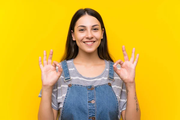 Fiatal Dungarees Felett Elszigetelt Sárga Háttér Mutató Jel Ujjakkal — Stock Fotó