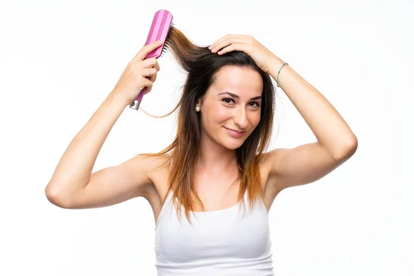 Молода жінка з волоссям розчісується над ізольованим білим тлом — стокове фото