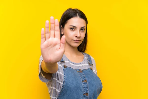 Giovane Donna Salopette Sfondo Giallo Isolato Facendo Gesto Arresto Con — Foto Stock