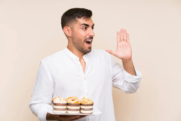 Hombre Guapo Sosteniendo Pastel Magdalenas Sobre Fondo Aislado Gritando Con — Foto de Stock